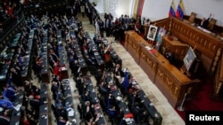 FILE - People raise their hands during the swear-in ceremony of Venezuela's National Assembly new term, in Caracas, Venezuela, Jan. 5, 2021.