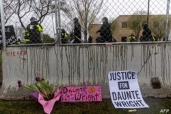 Flores y letreros dejados frente a una valla de seguridad al comienzo del toque de queda para protestar por la muerte de Daunte Wright, fallecido a manos de una oficial de policía en Brooklyn Center, Minnesota, el 12 de abril de 2021.