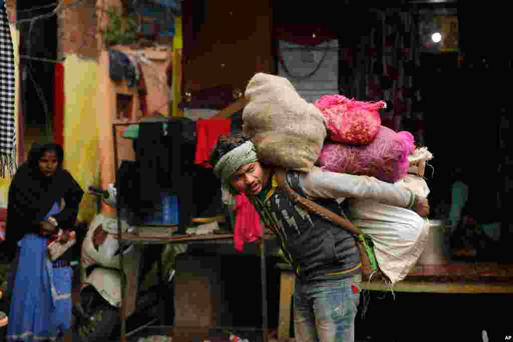A worker carries vegetables on his back at a market in Lucknow, India.