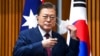 South Korean President Moon Jae-in removes his mask as he witnesses a signing ceremony at Parliament House, in Canberra, Australia, Dec. 13, 2021.