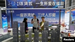 FILE - A salesman explains building types to customers at a real estate show in Shenzhen, Guangdong province, China, Oct. 12, 2024.