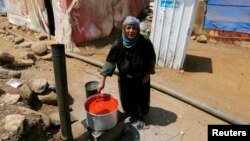 A Syrian woman cooks in front of her tent after she and her family fled from Raqqa in Syria, in Wazzani village in south Lebanon Aug. 30, 2014.