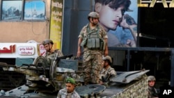 Lebanese army soldiers on their armored vehicle stand guard in Beirut, Oct. 15, 2021, at the site where deadly clashes erupted the previous day.