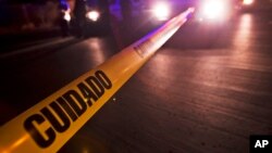 FILE - Police tape that reads in Spanish "Caution" marks off a crime scene in Mexico.