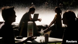 FILE - Students and visitors sit in front of a fountain at Harvard University in Cambridge, Massachusetts, Sept. 21, 2009.