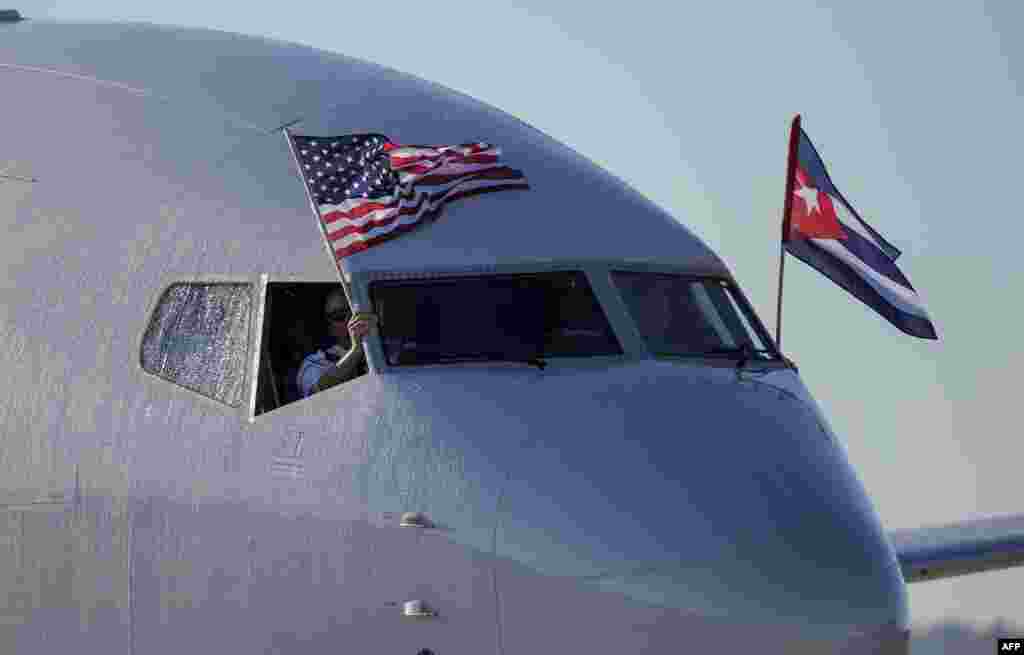 An American Airlines plane fluttering US and Cuba national flags is seen uppon arrival at Jose Marti International Airport becoming the first Miami-Havana commercial flight in 50 years, coinciding with the beginning of the tributes to late Cuban leader Fi