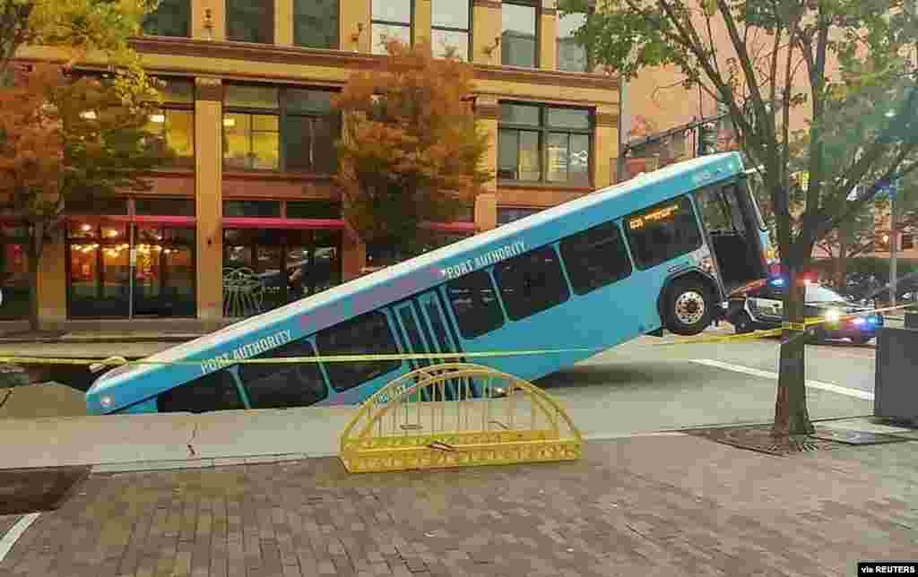 Front of a public bus sticks out of a sinkhole on 10th and Penn Avenue in Pittsburgh, Pennsylvania, in this picture obtained from social media.