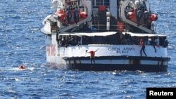 Para migran melompat dari kapal penyelamat Spanyol "Open Arms", dekat pantai Italia, Lampedusa, 20 Agustus 2019.