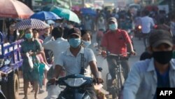 Commuters wearing face masks amid concerns over the spread of the COVID-19 coronavirus make their way on bikes in the Hlaing Tharyar township on the outskirts of Yangon on May 16, 2020. (Photo by Sai Aung Main / AFP)