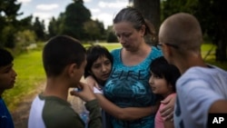 Olga Lopatkina embraces her adopted children in a park in Loue, western France, Saturday, July 2, 2022. (AP Photo/Jeremias Gonzalez)