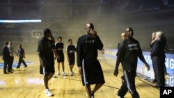 Miembros del equipo de los Timberwolves de Minnesota evacúan la arena de la Ciudad de México al llenarse ésta de humo.
