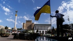 A woman looks over a row of destroyed Russian military vehicles on display at Maidan Square in Kyiv, Ukraine, Tuesday, Aug. 23, 2022. Kyiv official have banned mass gatherings through Thursday for fear of Russian missile attacks. (AP Photo/David Goldman)