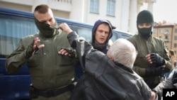 An elderly woman rips the mask off a police officer during an opposition rally to protest the official presidential election results in Minsk, Belarus, Sept. 12, 2020.