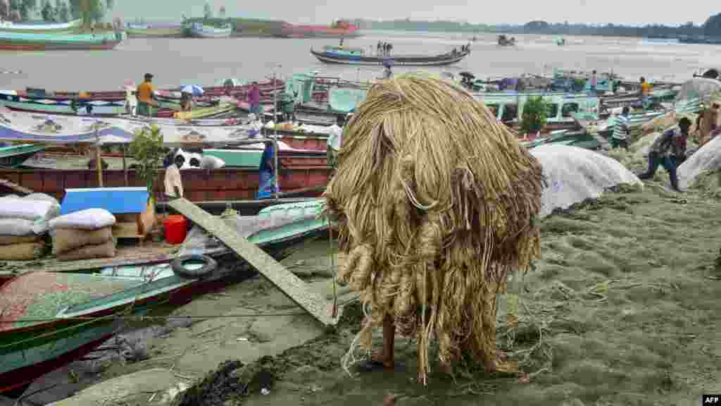 Radnik nosi jutu da je utovari u brod na ruralnoj pijaci u Munšigondžu u Bangladešu (Foto: AFP/ Munir Uz Zaman)