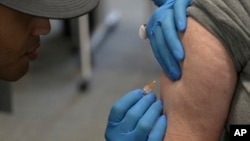 Matt Caldwell, left, a Lubbock Fire Department official, administers a measles, mumps and rubella vaccine to Clair May, 61, at the Lubbock Health Department in Lubbock, Texas, Feb. 26, 2025. 