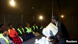 Les responsables électoraux comptent les bulletins de vote, alors que les bureaux de vote ferment après les élections générales dans la commune de Mbare, Harare, Zimbabwe, le 23 août 2023.