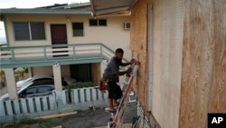 Un habitant pose des planches pour protéger les fenêtres d'une maison en prévision de l'ouragan Lane à Kapolei, Hawaï, le 22 août 2018,
