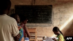 Voters wait as a electoral comission official checks a voter's roll at the polling station in Bangui, Central African Republic, March 14, 2021 during the country's legislative elections.