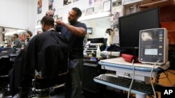 FILE - Barber Eric Muhammad, owner of A New You Barbershop cuts the hair of customer Marc M. Sims before measuring his blood pressure in Inglewood, California, March 11, 2018. 