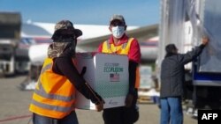 FILE - Workers unload 1.5 million doses of Moderna vaccine donated by the U.S. through the COVAX scheme, at the Armando Escalon aerial base, in San Pedro Sula, Honduras, June 27, 2021, in this handout picture released by the Honduran presidency.