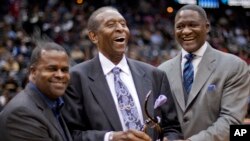 FILE - Earl Lloyd, center, is honored by Atlanta Mayor Kasim Reed, left, and Atlanta Hawks Vice President Dominique Wilkins during a halftime ceremony at an NBA game between Miami and Atlanta, Feb. 12, 2012.