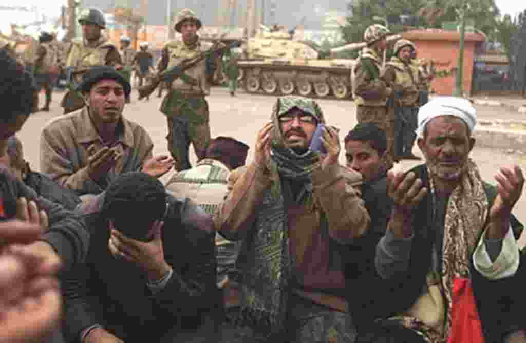 Egyptian anti-government demonstrators and members of the Egyptian Muslim Brotherhood movement pray in front of Egyptian soldiers at Cairo's Tahrir Square, February 7, 2011