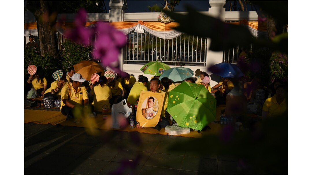 FILE - People gather holding a portrait of Thailand's King Maha Vajiralongkorn along a sidewalk near the Grand Palace in Bangkok, May 3, 2019, ahead of King Vajiralongkorn's coronation. which will take place from May 4 to 6.
