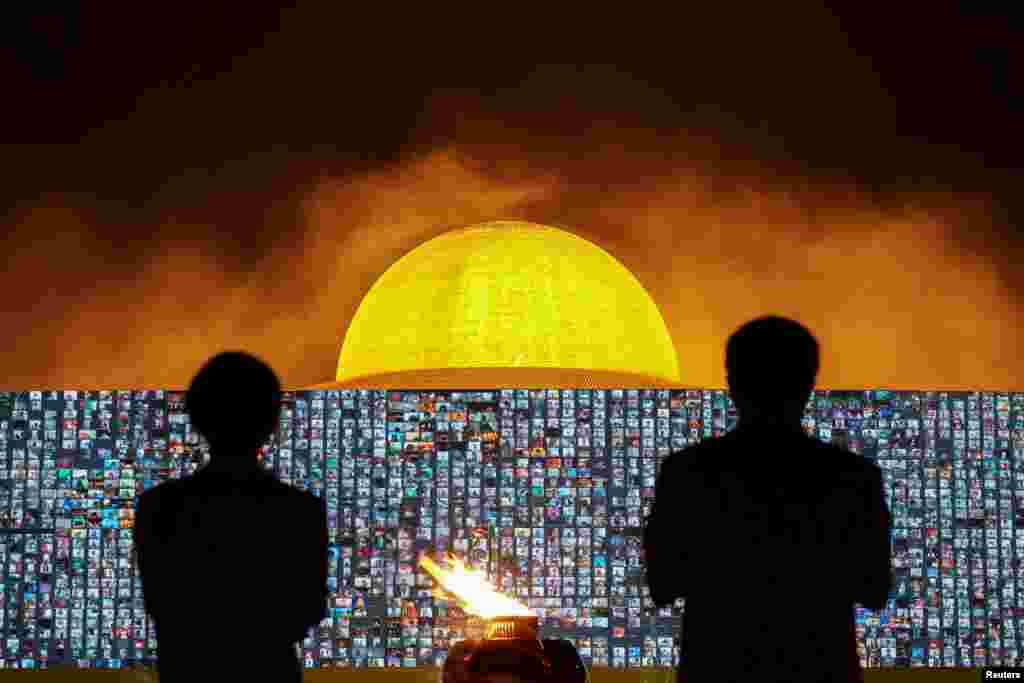 People pray as screens show devotees gathering via Zoom application during a ceremony to commemorate Makha Bucha Day at the Wat Phra Dhammakaya temple, following the spread of coronavirus, in Pathum Thani province, Thailand.
