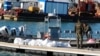 FILE - Tunisian coast guard members stand next to the dead bodies of migrants in the port of Sfax, Tunisia, Dec. 24, 2020. 