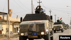 Peshmerga forces ride on military vehicles in the town of Bashiqa, after it was recaptured from the Islamic State, east of Mosul, Iraq, Nov. 9, 2016.