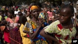 Women wait in line to have their children vaccinated against measles, at a makeshift camp housing people displaced by violence at a monastery in the Boy Rabe district of Bangui, Central African Republic, Sunday, Jan. 5, 2014. Concerned that crowded and un