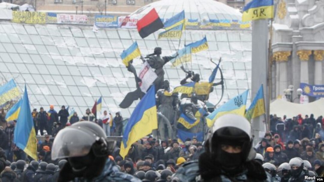 Pengunjuk rasa integrasi pro-Uni Eropa berdiri di belakang barisan polisi anti huru hara di Lapangan Kemerdekaan di Kiev, Ukraina (11/12).