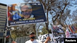 Una persona sostiene una pancarta que representa al presidente de Chile, Sebastián Piñera, y que dice "el acusado que vendió barato al país" durante una protesta frente al edificio del Congreso, en Valparaíso, Chile, el 16 de noviembre de 2021.