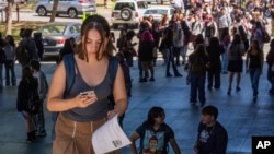 FILE - Student Keiran George uses her cellphone as she steps outside the Ramon C. Cortines School of Visual and Performing Arts High School in downtown Los Angeles on Tuesday, Aug. 13, 2024. (AP Photo/Damian Dovarganes)