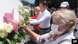 Ljudi polažu cveće na vozila u centru Sarajeva, kojim će se posmrtni ostaci osam žrtava masakra u Srebrenici prevesti do mesta gde će biti sahranjeni (Foto: AP)