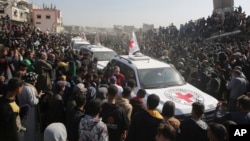 A crowd surrounds Red Cross cars as they arrive at the site for the handover of Thai and Israeli hostages in Khan Younis, southern Gaza Strip, Jan. 30, 2025.