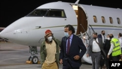 Wartawan AS Danny Fenster (kiri), yang dipenjara di Myanmar, turun dari pesawat bersama mantan diplomat AS Bill Richardson setibanya mereka di Bandara Internasional Hamad di ibu kota Qatar, Doha, pada 15 November 2021. (Foto: AFP)