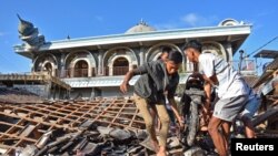 Warga sedang mengambil sepeda motor dari rumah yang rusak akibat gempa kuat di Gunungsari, Lombok Barat, 6 Agustus 2018. (Antara Foto/Ahmad Subaidi/ via Reuters)
