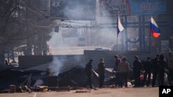 Pro-Russia activists are seen behind a barricade with Russian flags in front an entrance of a regional office of Ukraine's Security Service in Luhansk, April 8, 2014.