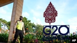 FILE - Seorang polisi berjaga di dekat papan penjuk Pertemuan Para Menlu G20 di Nusa Dua, Bali, 7 Juli 2022. (AP/Dita Alangkara, Pool)