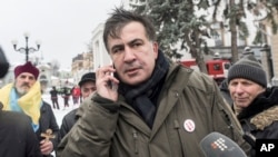 Mantan presiden Georgia Mikheil Saakashvili, (tengah), dikelilingi oleh pendukungnya berbicara di telepon saat mereka berkemah di luar parlemen menuntut pengunduran diri presiden Ukraina, di Kiev, Ukraina, Rabu 6 Desember 2017.