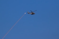 Un helicóptero de ataque israelí pasa por el sistema de defensa aérea Cúpula de Hierro mientras se lanza para interceptar un cohete disparado desde la Franja de Gaza, en la frontera israelí de Gaza, en el sur de Israel, el jueves 13 de mayo de 2021.