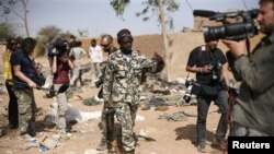Un soldat malien demande aux journalistes de quitter l'endroit où a eu lieu une frappe de l'armée française, à Konna, 688 kms au nord de Bamako, le 26 jan. 2013