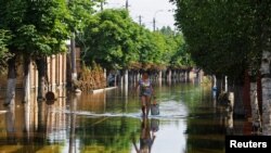 Una mujer camina por una calle después de que la inundación retrocedieran tras el colapso de la represa Nova Kakhovka en el curso del conflicto entre Rusia y Ucrania, en la ciudad de Hola Prystan en la región de Kherson, Ucrania controlada por Rusia, el 16 de junio de 2023.