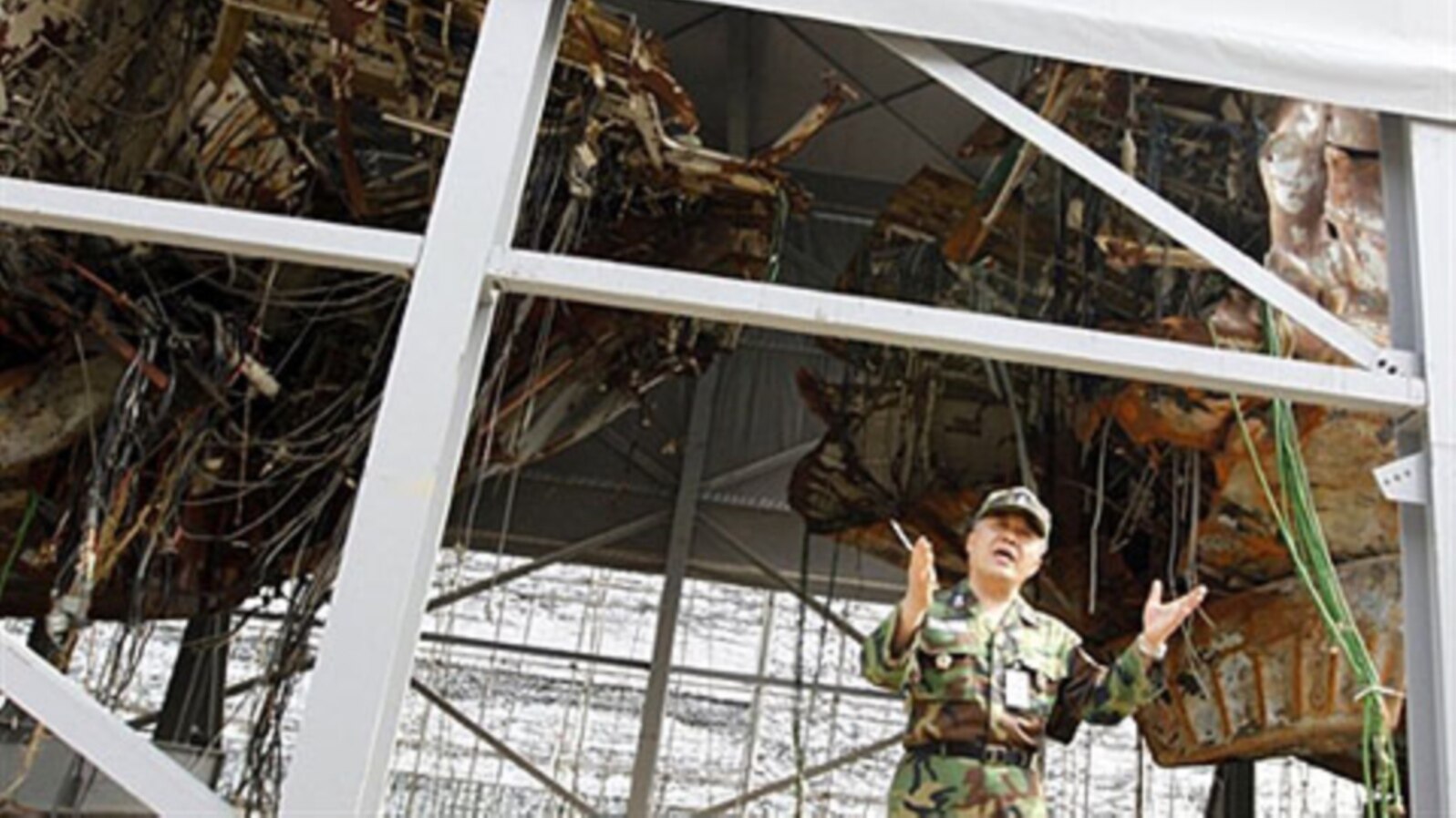 FILE - A South Korean naval officer talks in front of wreckage of the salvaged naval vessel Cheonan, May 19, 2010.