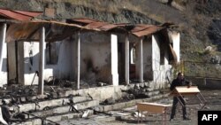 A man carries a table near a destroyed house in the country side outside the town of Kalbajar on November 23, 2020. - Azerbaijan said on November 20, 2020, its troops entered a district bordering Nagorno-Karabakh handed back by Armenian separatists…