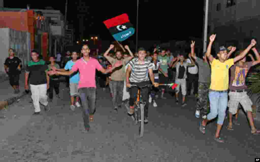 People in Tajura, a suburb of Tripoli, celebrating in the early morning on August 22, 2011 after Libyan rebels surged into Tripoli in a final drive to oust leader Moamer Kadhafi, seizing swathes of the capital including the symbolic Green Square and arres