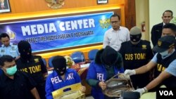 Dua tersangka penyelundupan 4 Kg shabu menunjukkan bagaimana shabu diselundupkan di dalam tas perempuan, di Bandara Yogyakarta, 28/12/2014. 