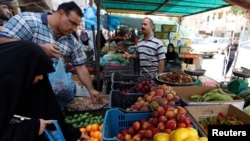 FILE - Residents shop for fruits and vegetables at a market in Baghdad's Karrada district. Iraq relies on imports from neighbors like Iran, Syria and Turkey for much of its consumer goods.