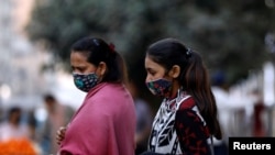 Women with masks against COVID-19 walk outside a market in Karachi, Pakistan, Jan. 25, 2021.